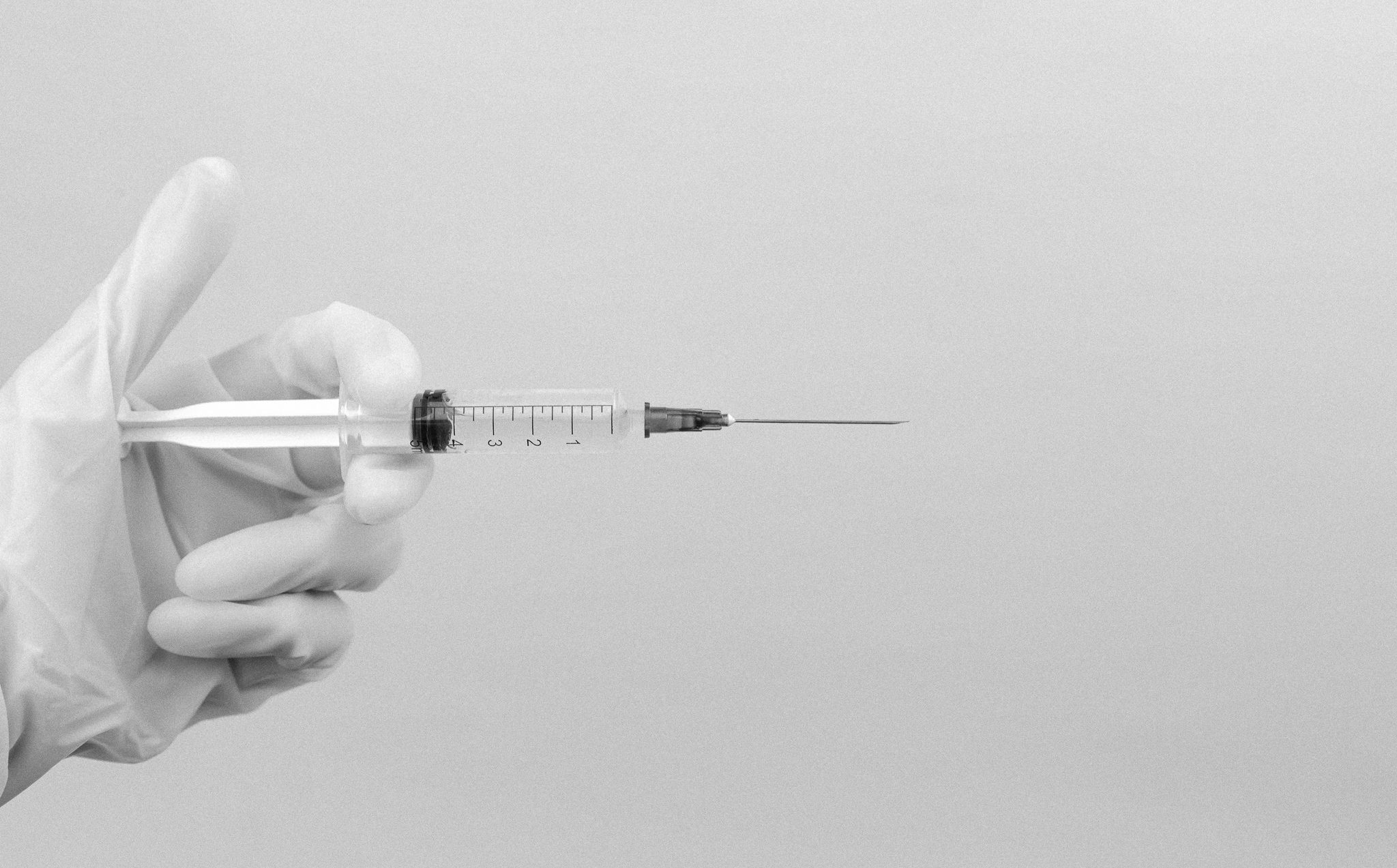 Hand holding syringe and needle horizontally